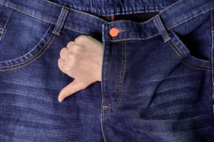 A hand with 'thumb down' gesture sticking out the zipper of jeans